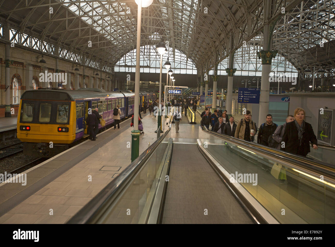 Manchester-Bahnhof mit Zug an der Plattform und Menge der Pendler verlassen des Bereiches per Rolltreppe Stockfoto