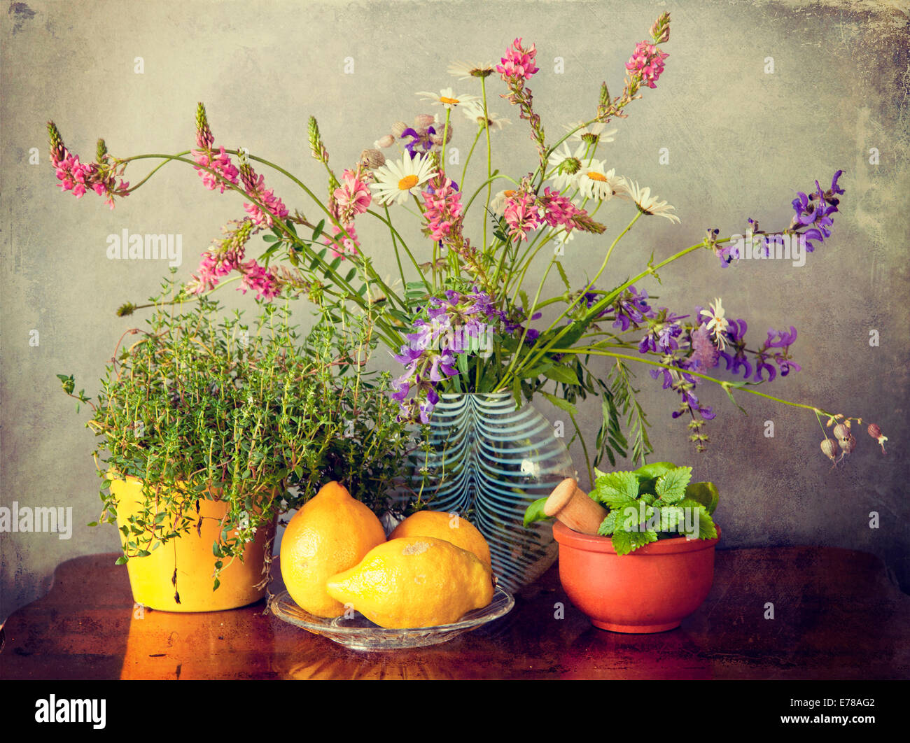 Kräuter aus dem Garten, Wiesenblumen in Vase und Zitrone Obst. Grunge Texturen und Instagram-Retro-Effekt Stockfoto