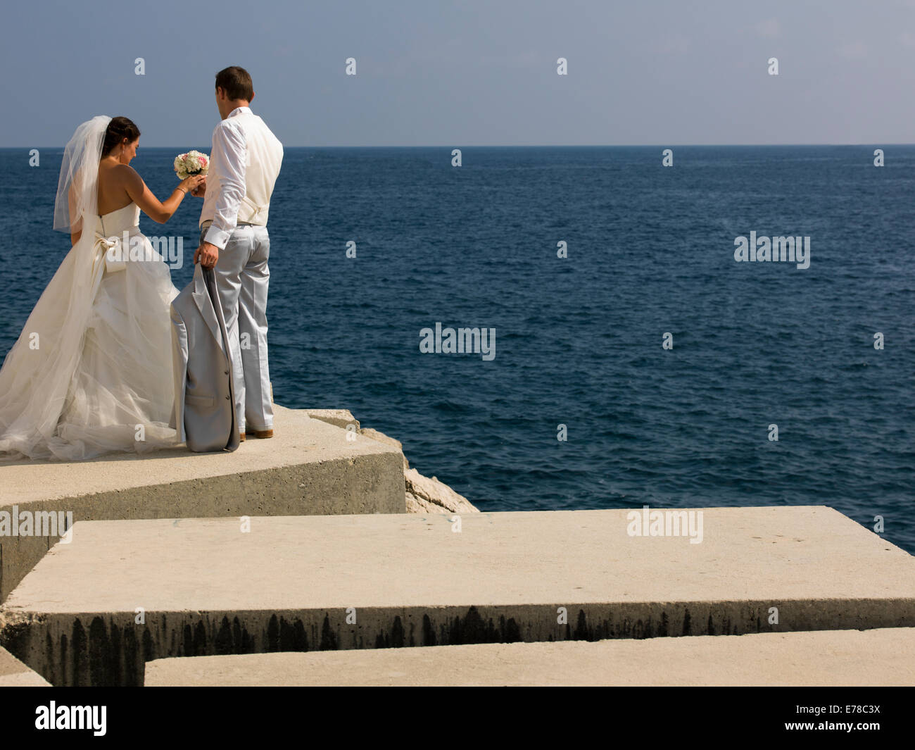 Braut und Bräutigam stehen auf Felsen am Meer Stockfoto