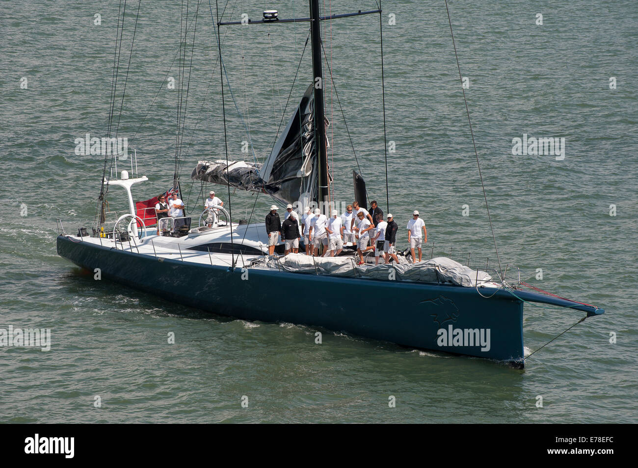 Mannschaft steht auf dem Deck einer Luxusyacht Segeln vor der Küste von Southampton, England. Stockfoto