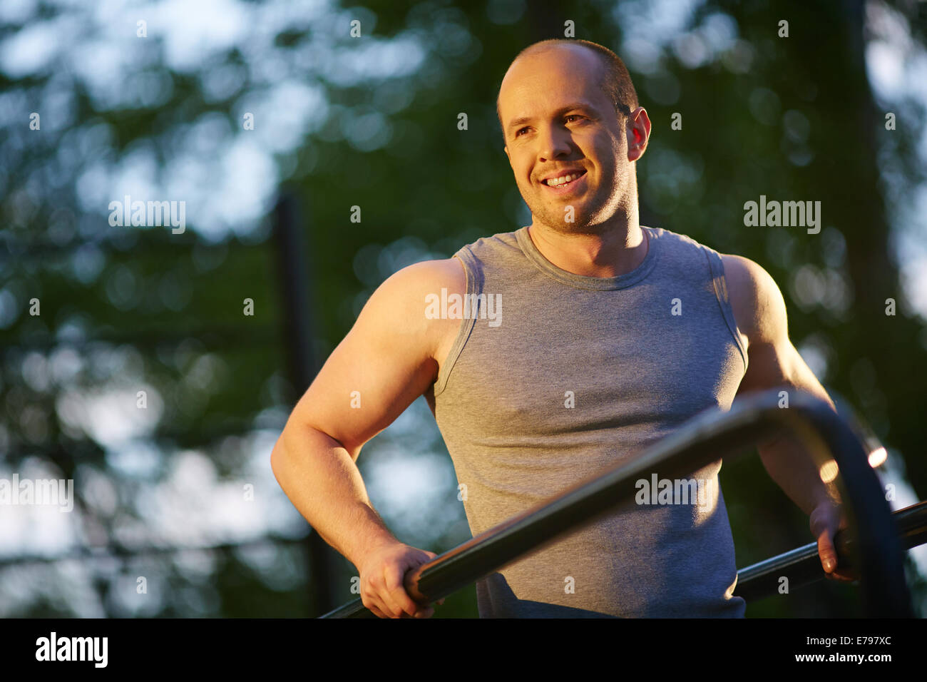 Lächelnder Mann training auf Sportausrüstung außerhalb Stockfoto