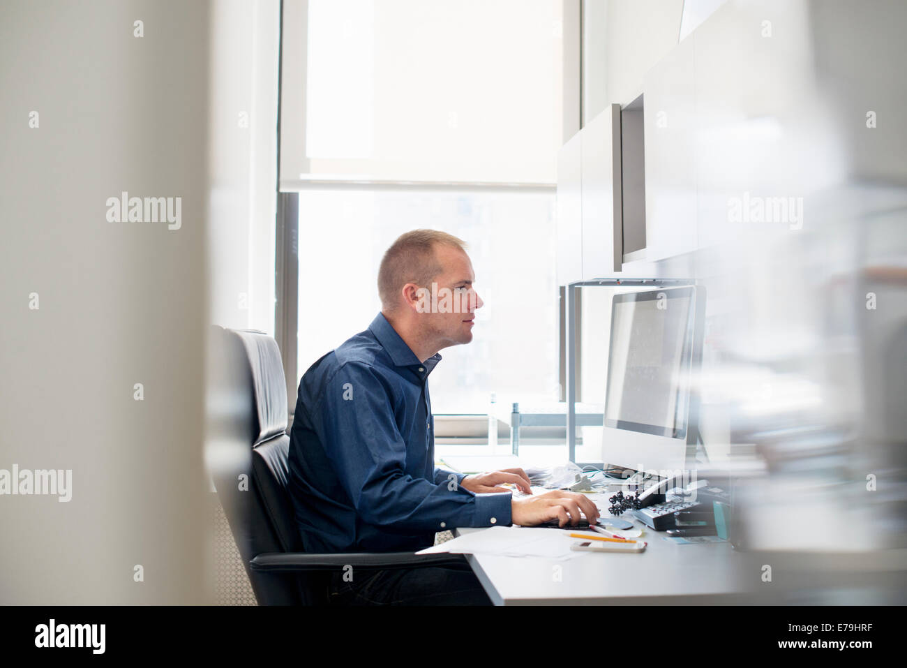 Ein Mann in einem Büro an einem Schreibtisch mit einer Computermaus. Auf eine Aufgabe konzentrieren. Stockfoto