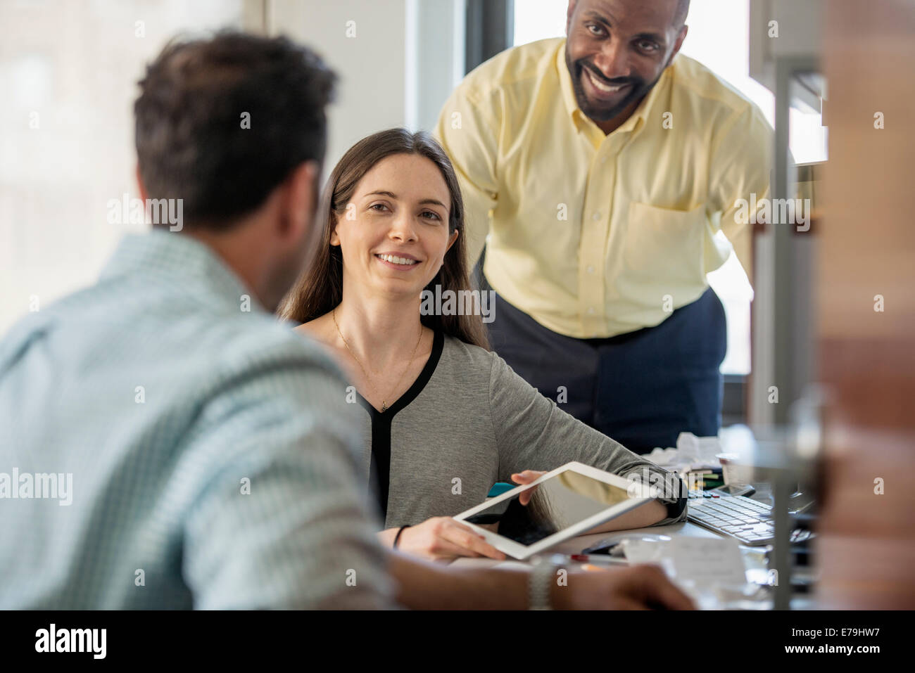 Drei Menschen in einem Büro, zwei Männer und eine Frau mit Computer-Monitor und digital-Tablette. Stockfoto