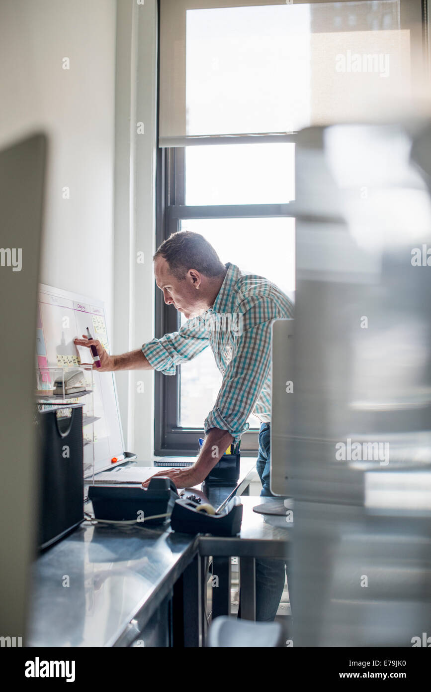 Büroalltag. Ein Mann im stehen arbeiten und Notizen auf einer Wandkarte zu machen. Projekt-Management. Stockfoto