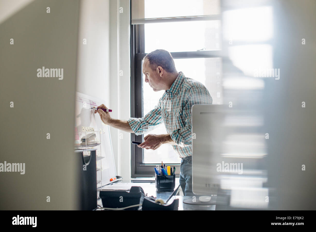 Büroalltag. Ein Mann im stehen arbeiten und Notizen auf einer Wandkarte zu machen. Projekt-Management. Stockfoto