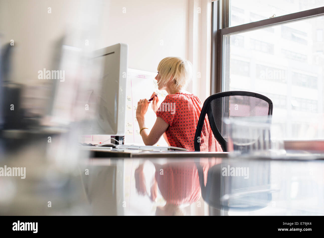 Büroalltag. Eine junge Frau an einem Schreibtisch arbeiten. Stockfoto