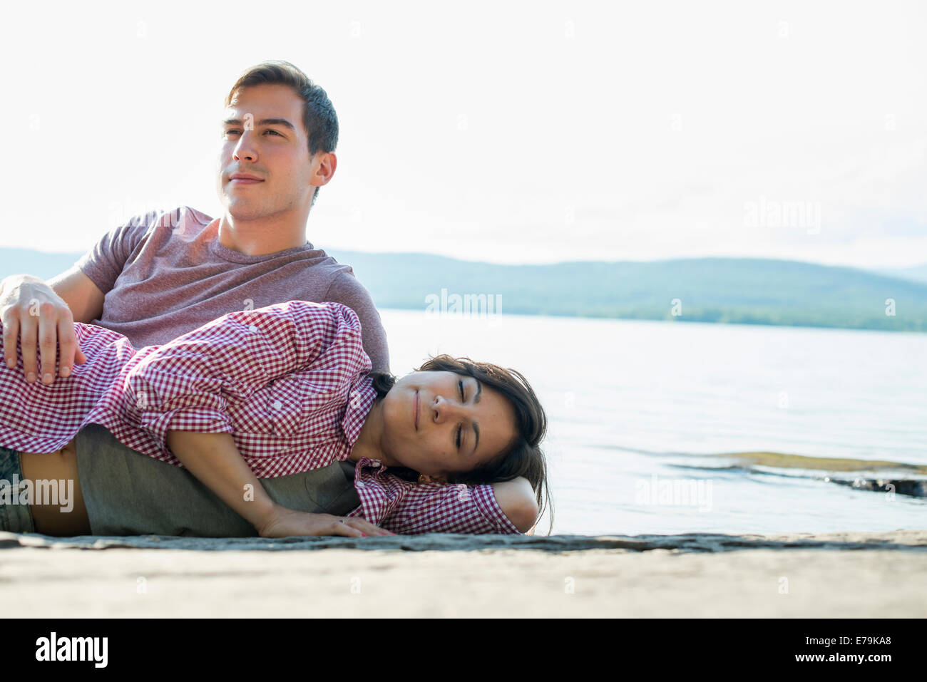 Ein paar entspannende, liegend auf einem hölzernen Steg an einem See im Sommer. Stockfoto