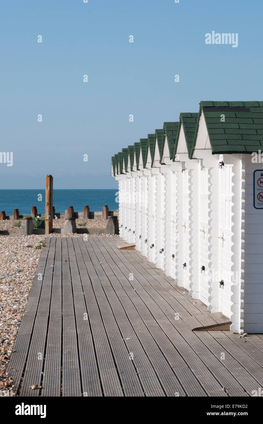 Weiße Strandhütten an einem sonnigen Tag in Eastbourne, East Sussex mit Belag vorne drauf Stockfoto