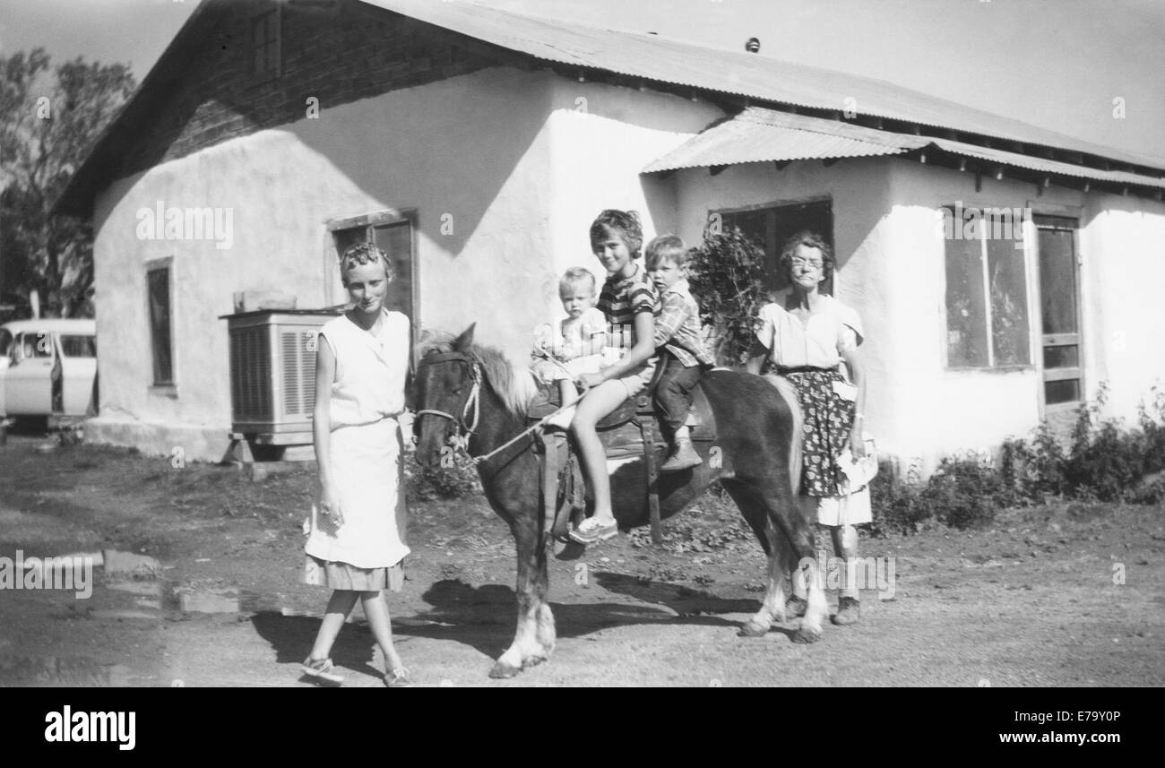 Eine Familie von Erwachsenen und Kindern vor ihrem Adobe-Haus in Santa Fe, New Mexico, ca. 1960. Stockfoto