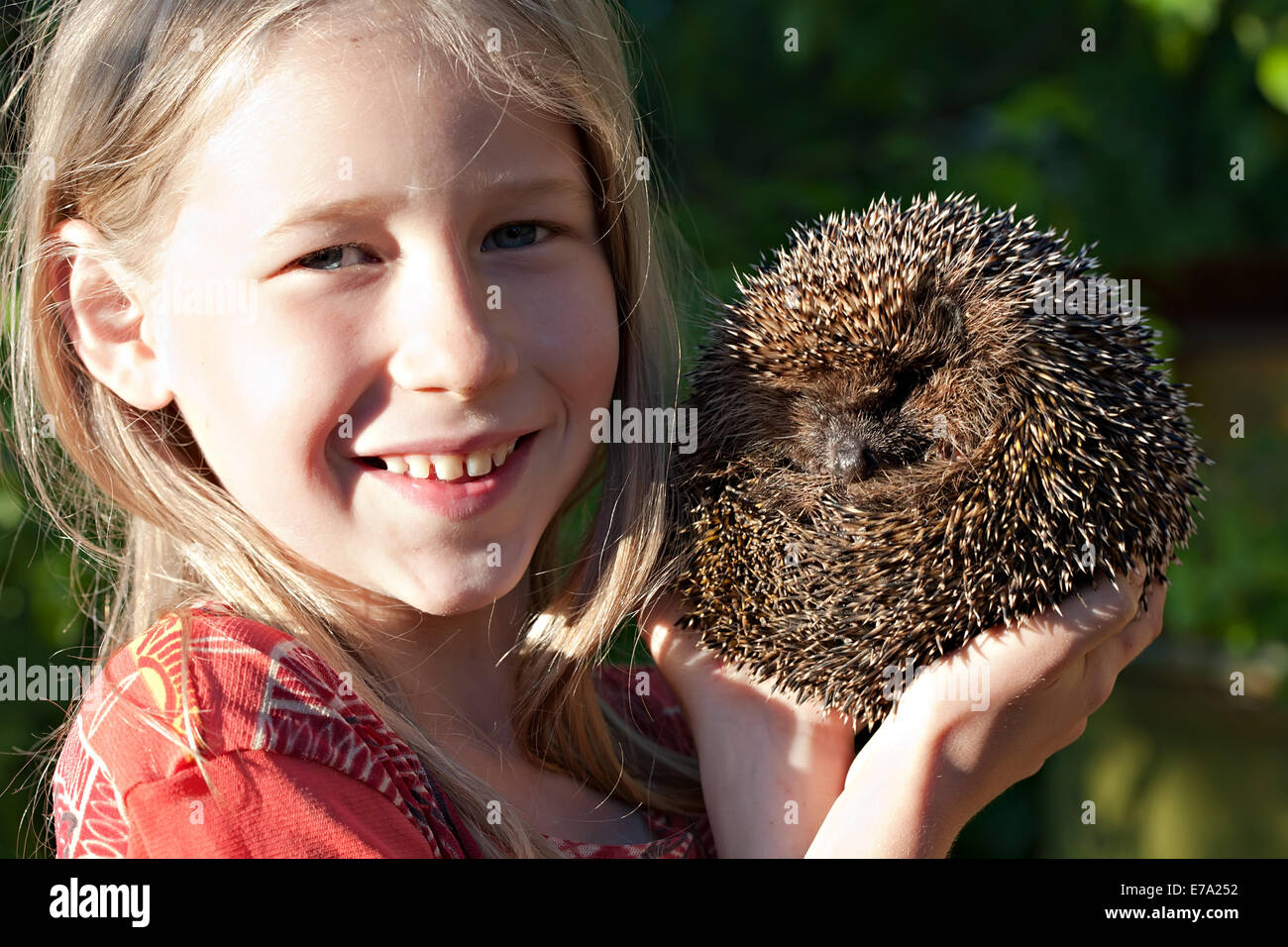 lächelndes Mädchen mit niedlichen Igel-Ball in Hand Stockfoto