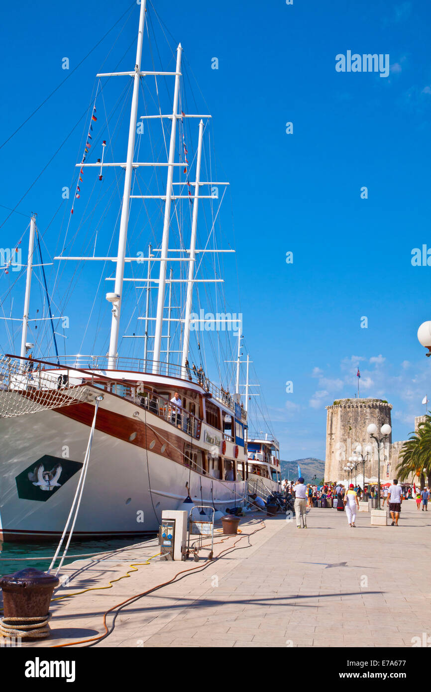 Kroatien, Trogir: Touristen auf das Meer promenade mit touristischen Kreuzfahrtschiffe vor Anker und die Aussicht auf die Burg Turm Kamerlengo Stockfoto