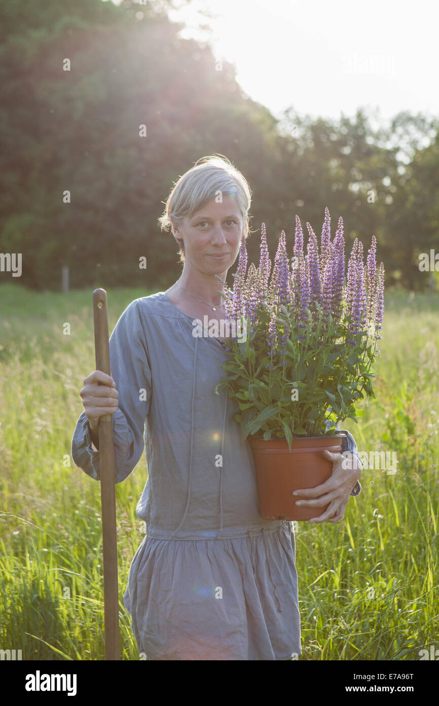 Porträt von zuversichtlich Reife Frau mit Blumentopf im Garten Stockfoto