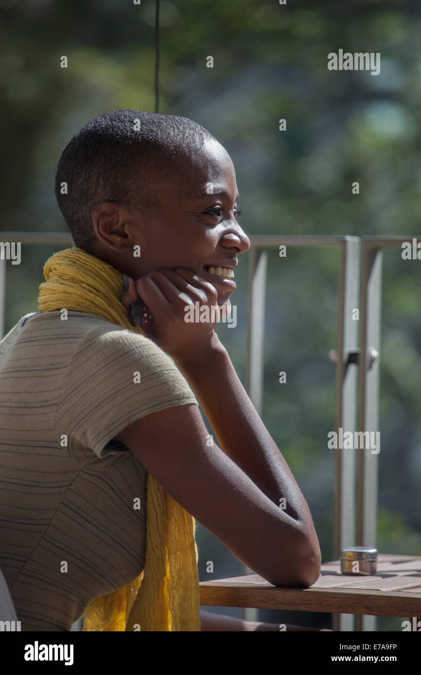 Seitenansicht der lächelnde junge Frau sitzt am Tisch auf Hof Stockfoto