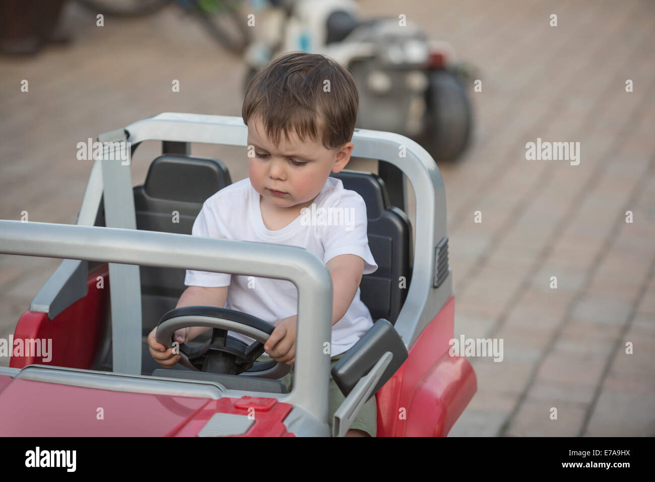 Süsser Boy in Spielzeugauto im Freien sitzen Stockfoto