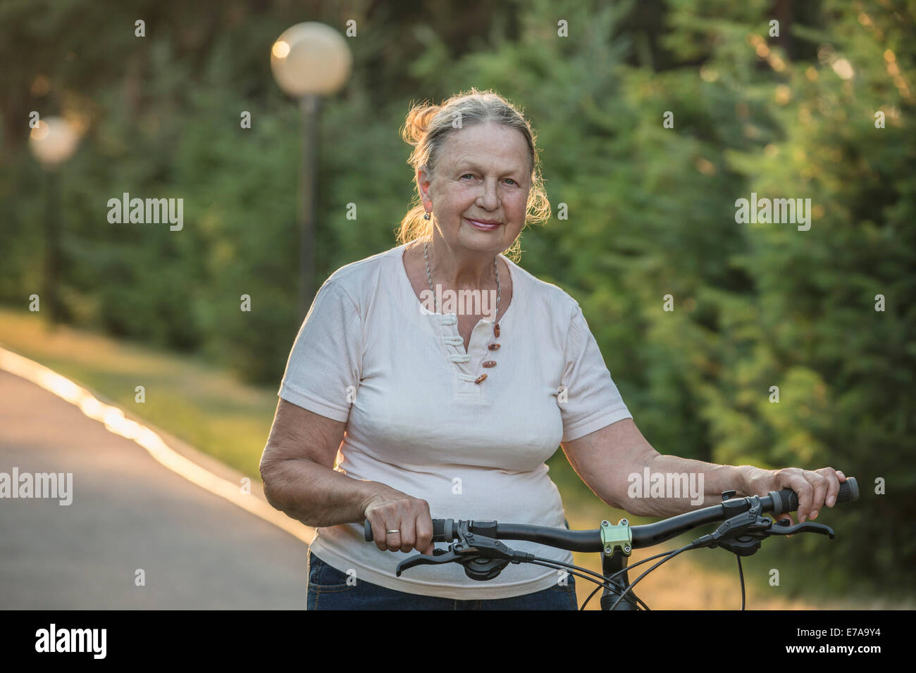 Portrait von senior Frau mit dem Fahrrad im park Stockfoto