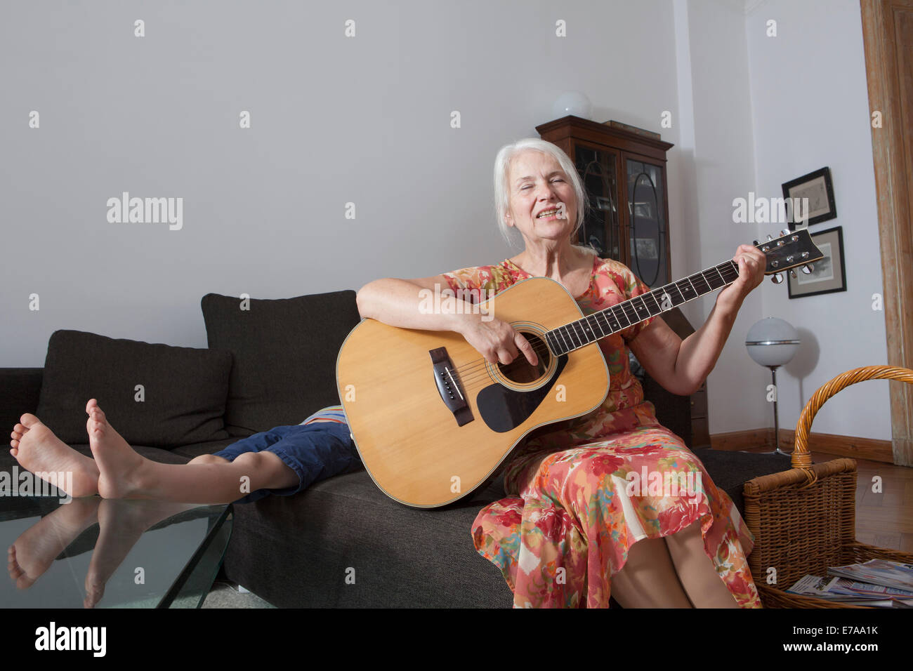 Ältere Frau Gesang Lied spielend Gitarre zu Hause Stockfoto