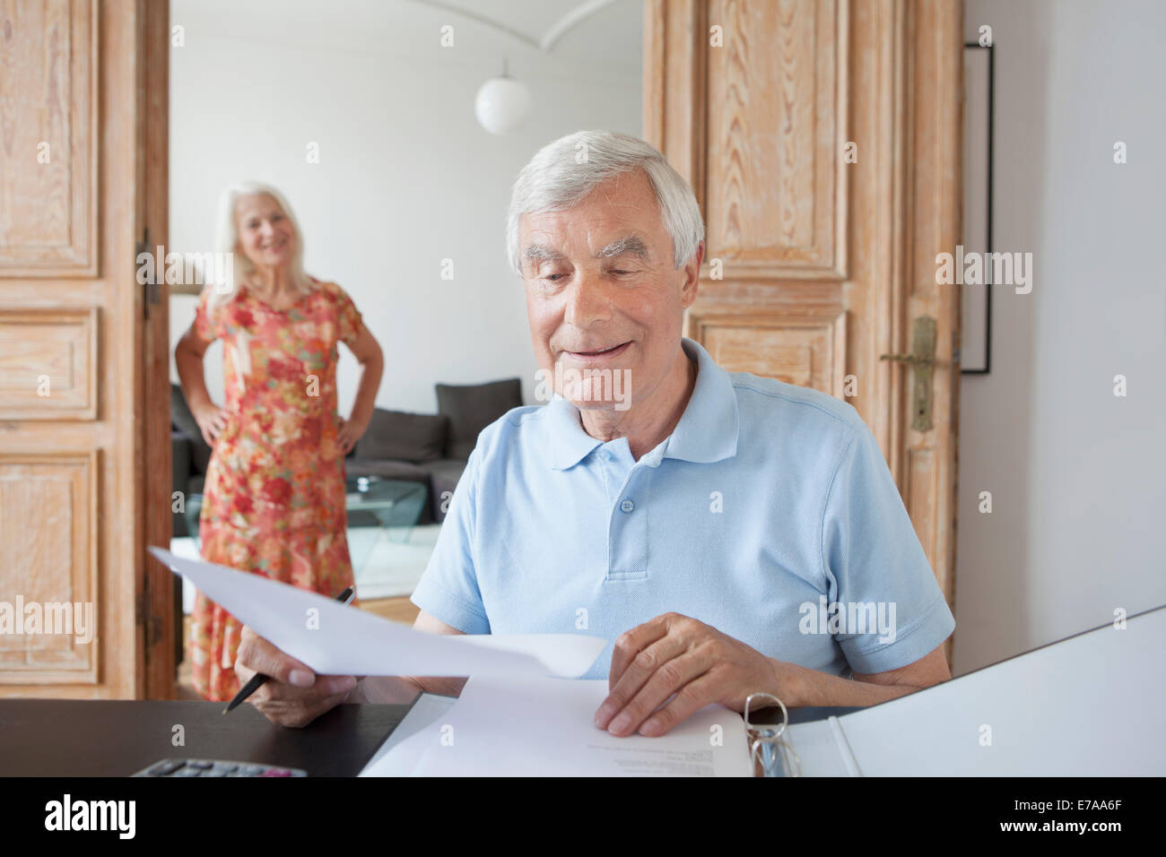 Senior woman, die Überprüfung der finanziellen Dokumente zu Hause mit Frau im Hintergrund Stockfoto