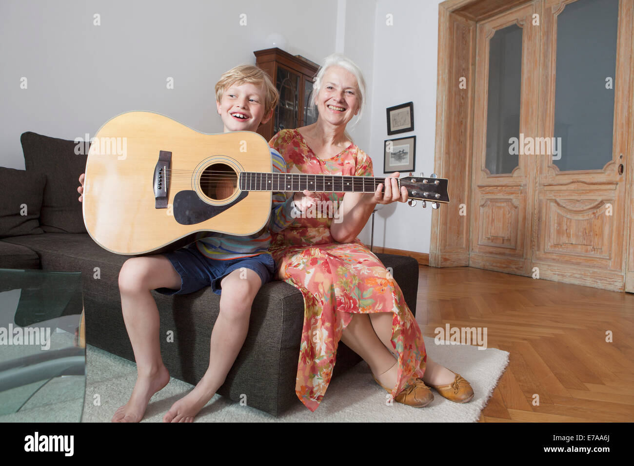 Glücklich Enkel und Oma mit Gitarre sitzt zu Hause auf sofa Stockfoto