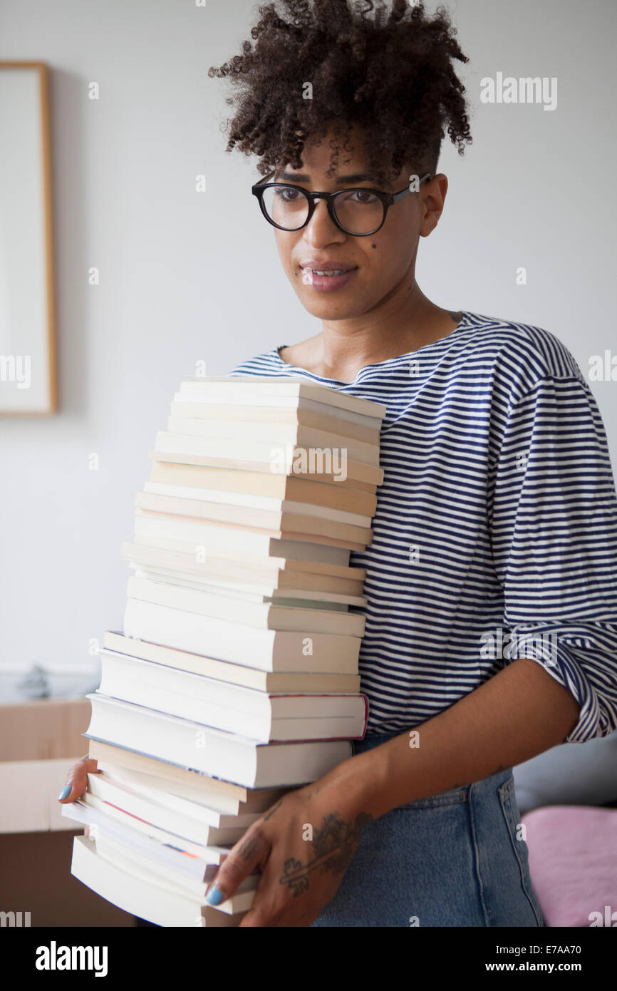 Junge Frau, die Stapel von Büchern zu Hause Stockfoto