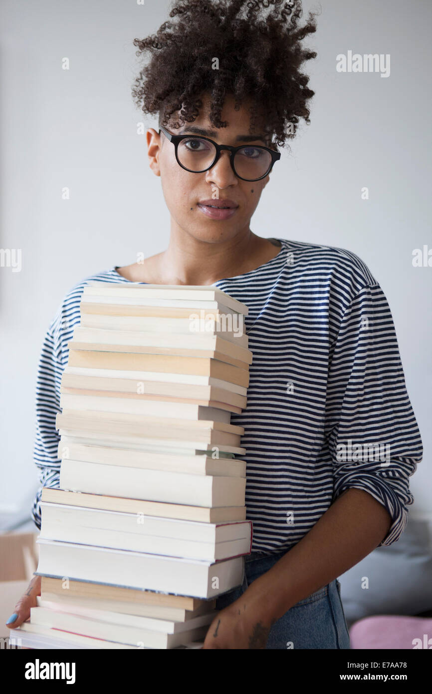 Porträt der selbstbewusste junge Frau tragen Stapel Bücher zu Hause Stockfoto