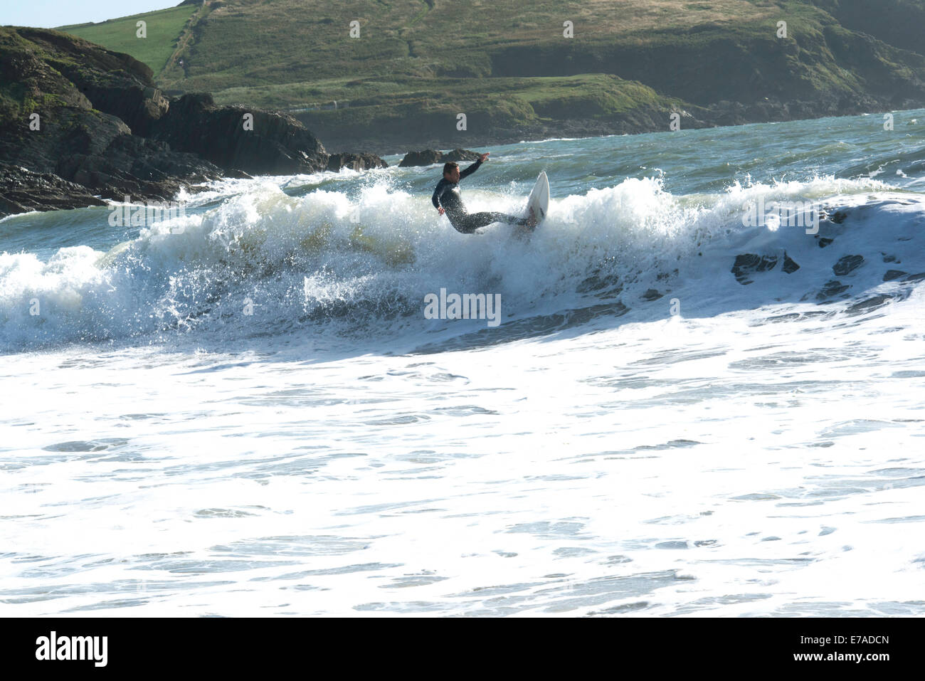 Juni 2014: Action shot der Surfer auf der Welle an der Challaborough Bay, South Devon Küste im Hintergrund Stockfoto