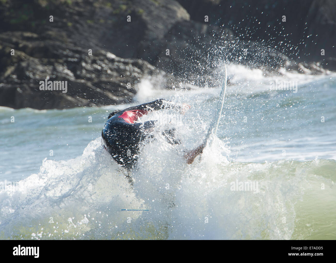 Action shot der Surfer auf der Welle mit Felsen im Hintergrund Stockfoto