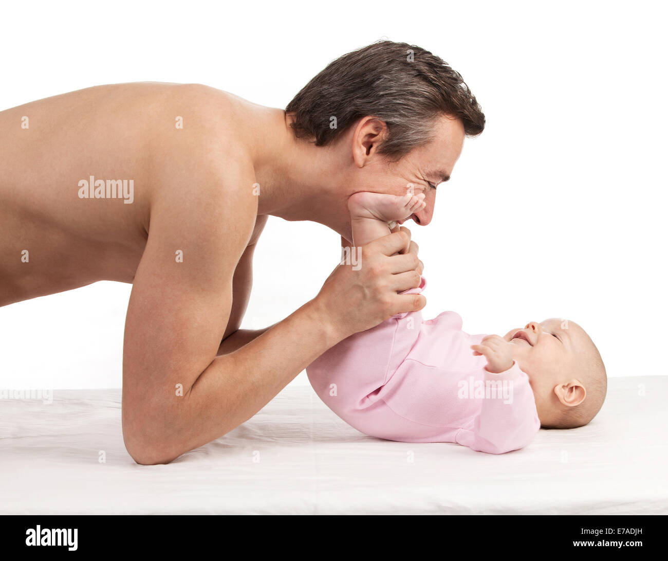 Junger europäischer Abstammung Vater beugte sich über neugeborenen Sohn auf weißem Hintergrund Stockfoto