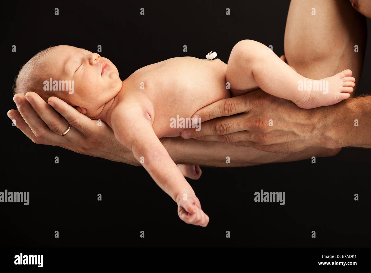 Neugeborenen jungen liegen auf seines Vaters Arme auf schwarzem Hintergrund Stockfoto
