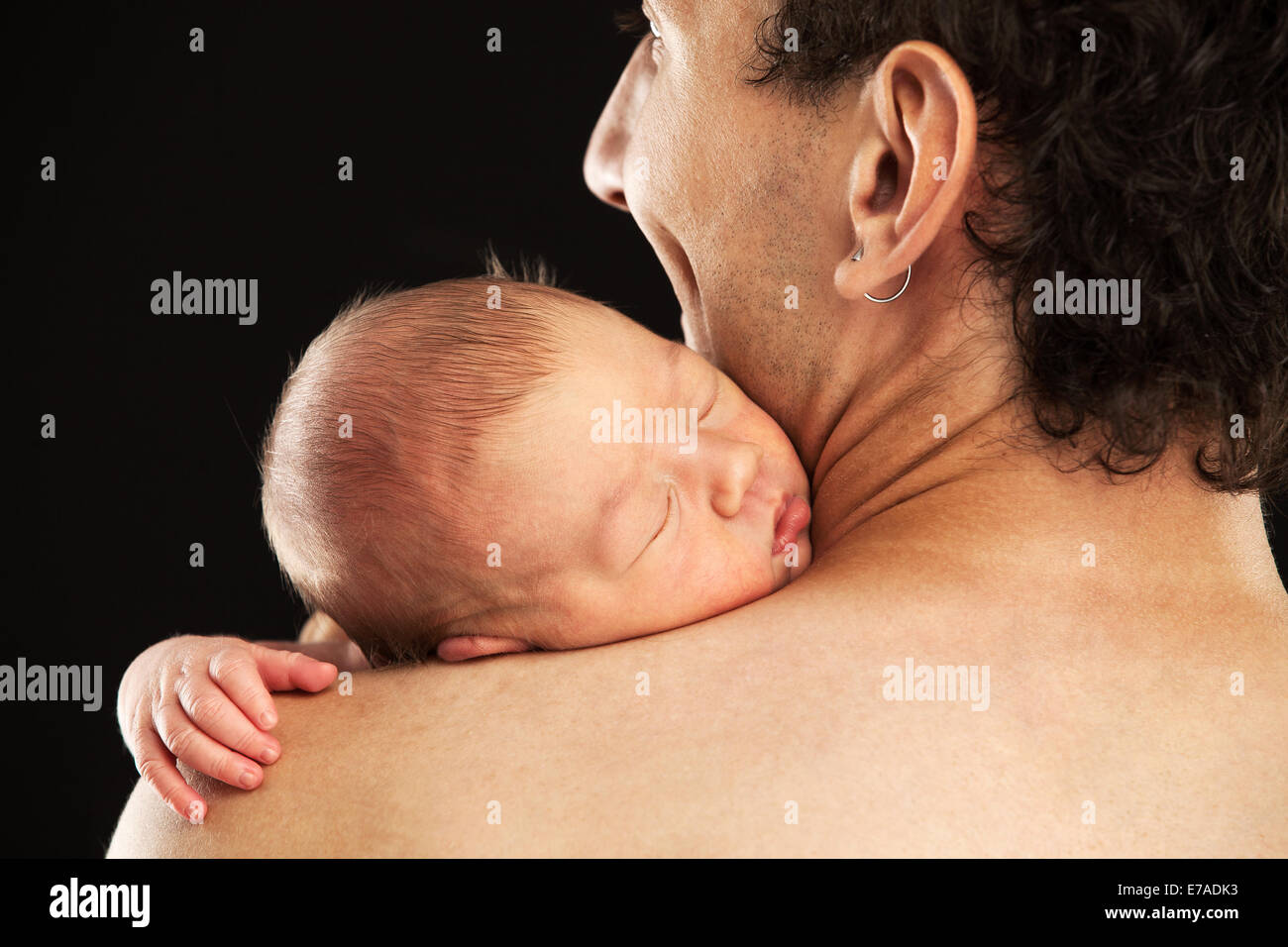 Neugeborene jungen schlafen auf seines Vaters Schulter über schwarzen Hintergrund Stockfoto