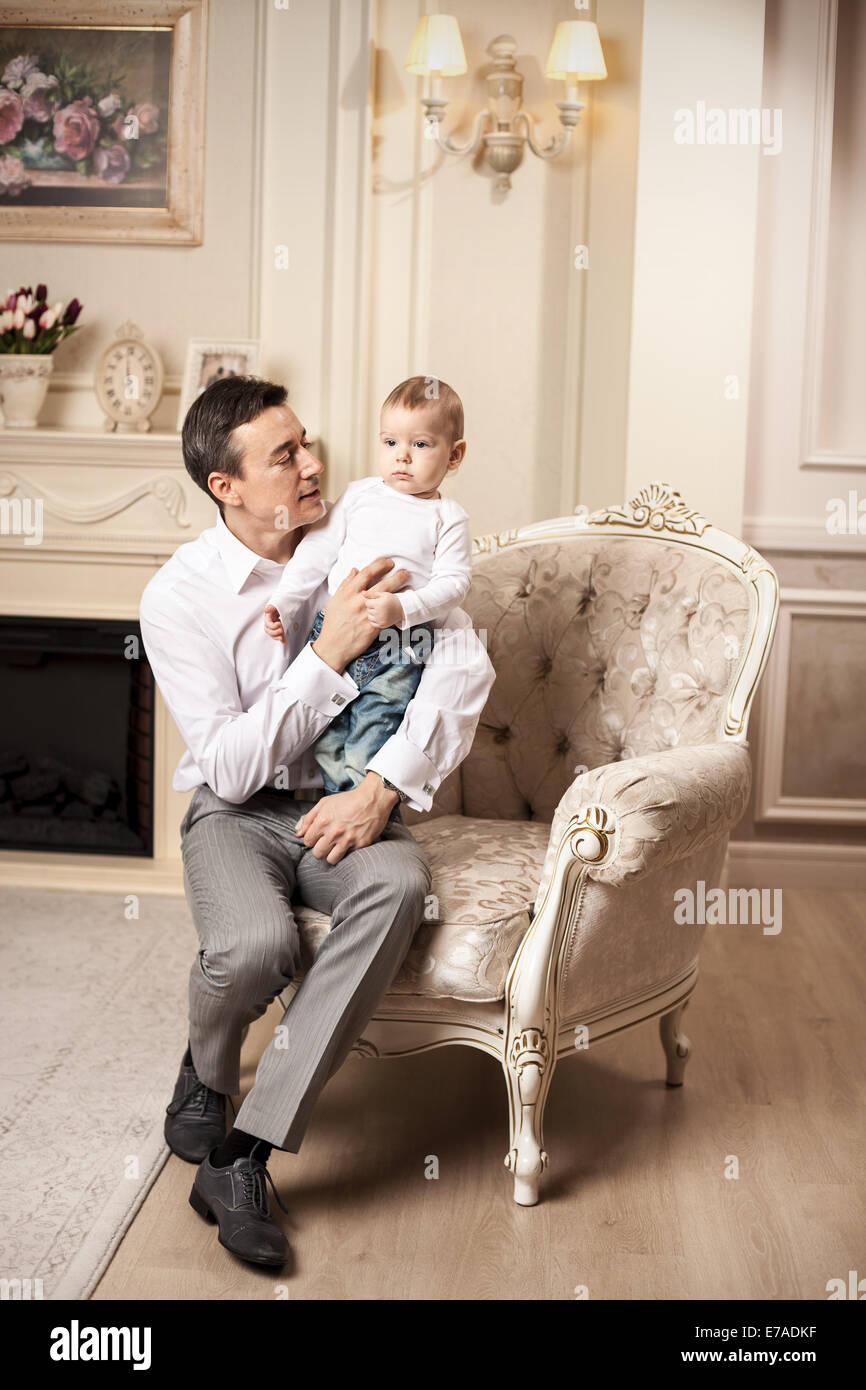 Junger Mann mit Sohn sitzen im Sessel im Wohnzimmer Stockfoto
