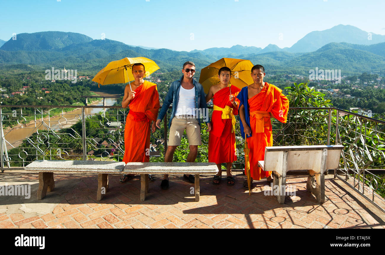 Reisende mit buddhistischen Mönchen in einem Tempel in Luang Prabang, Laos posiert. Stockfoto