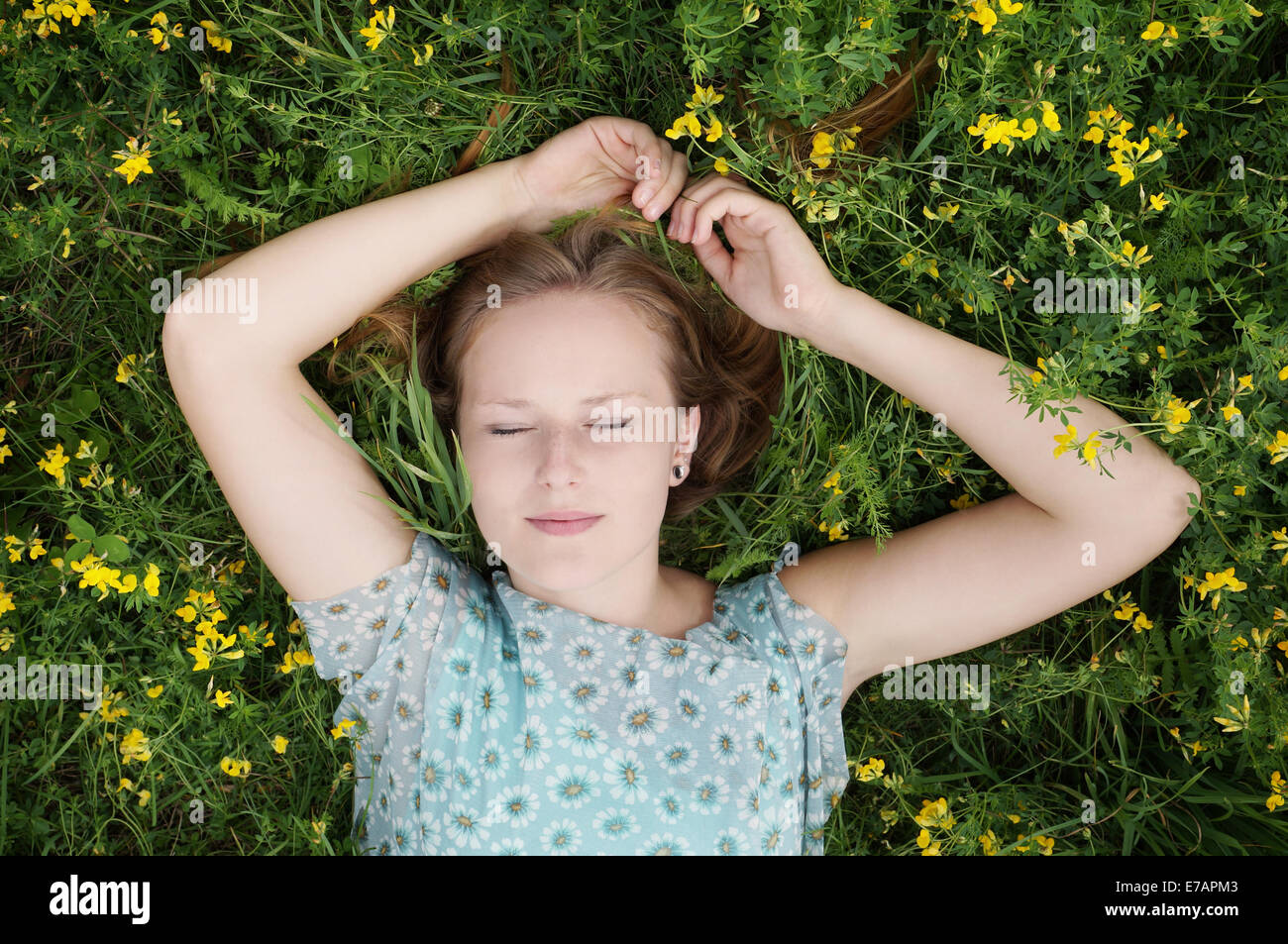 junge Frau schläft in einer Blumenwiese Stockfoto