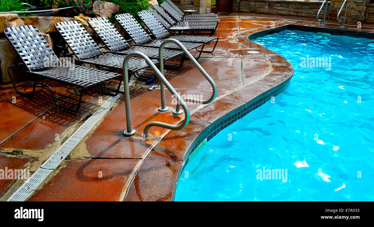 Liegestühle, Schwimmbecken mit blauem Wasser Stockfoto