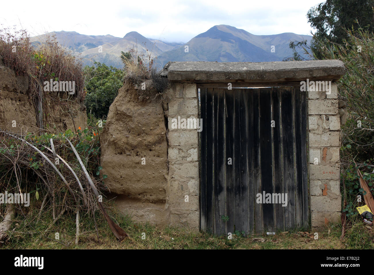Ein hölzernes Tor in einer Adobe-Wand auf einem Bauernhof in Cotacachi, Ecuador Stockfoto