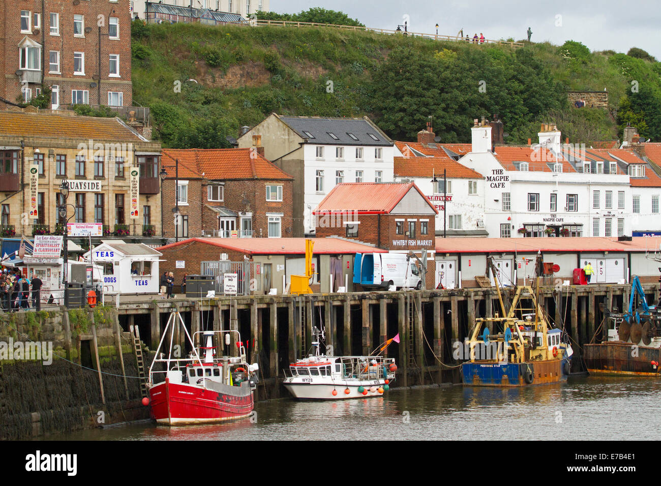 Bunte Fischerboote vertäut im Hafen von Whitby mit Gebäuden der englischen Küstenstadt Urlaub gruppierten entlang des Kais Stockfoto