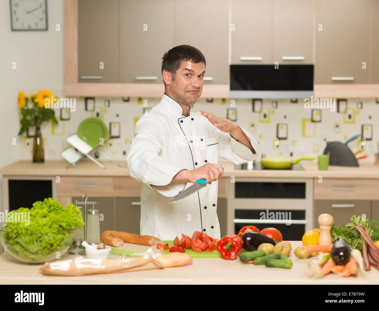Kaukasische Koch, stand vor Küchentisch mit Gemüse, halten Messer, Kämpfer Geste Stockfoto