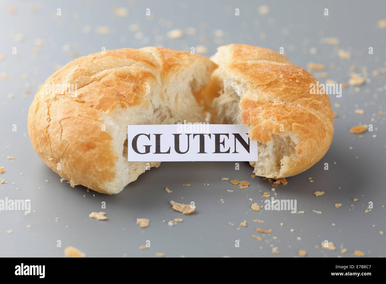 Stück Papier mit dem Wort Gluten in einem Brötchen. Zöliakie-Konzept. Stockfoto