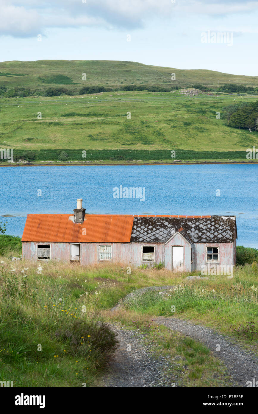 Verfallene Kleinbauern Häuser durch ein Loch in der Landschaft auf der Isle Of Skye Scotland UK eine mit einem roten Blechdach. Stockfoto