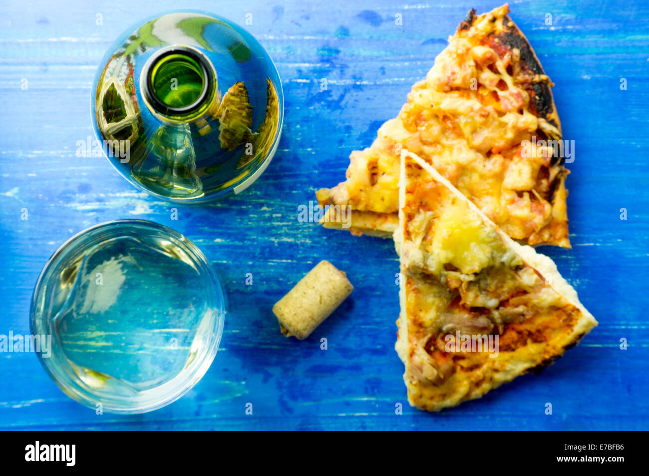 Weißwein und Pizza und eine Flasche aus Glas auf einem blauen Hintergrund von oben Stockfoto