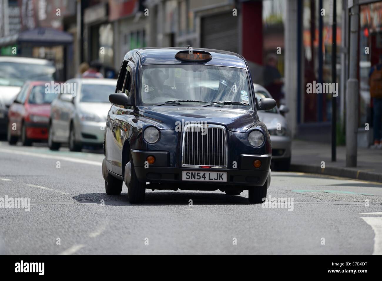 Ein Taxi/schwarzes Taxi, das entlang einer Stadtstraße, England, fährt Stockfoto