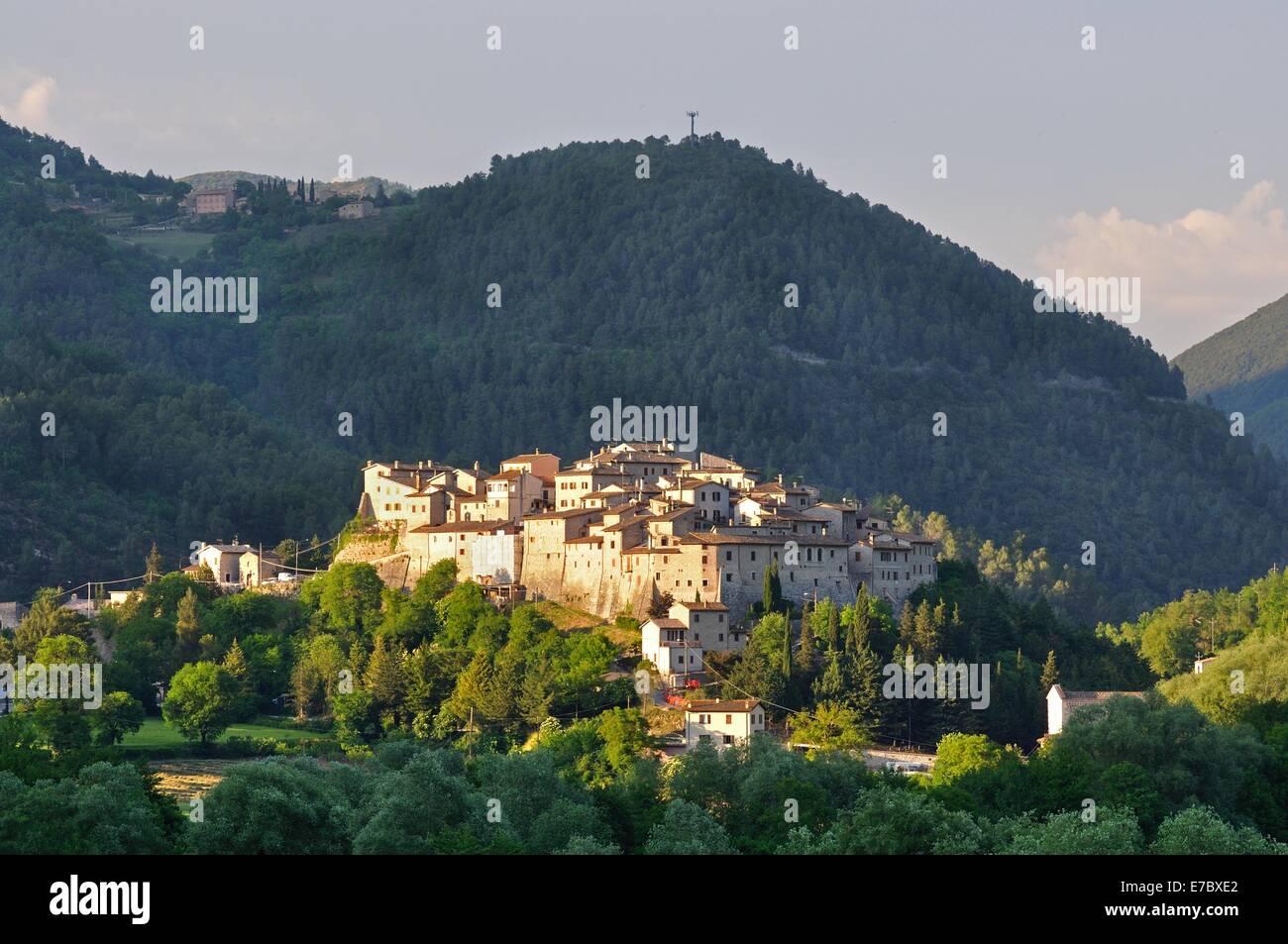 Die Sonne scheint auf einer Hügel-Stadt in Italien, befinden sich die bewaldeten Hügel hinter im Schatten Stockfoto