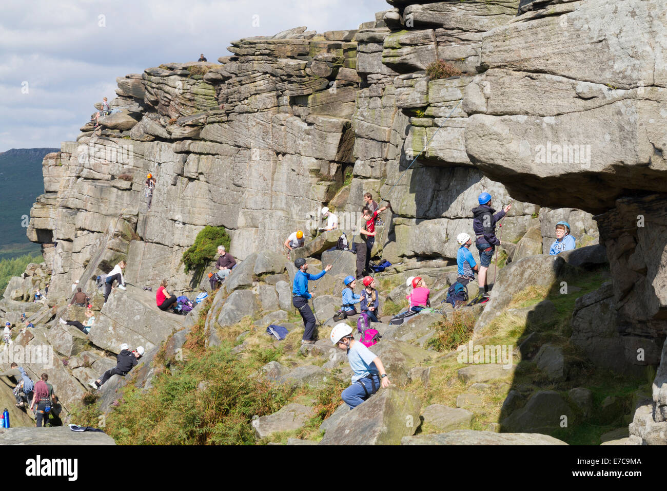Große Gruppe junger Menschen, die lernen, wie man Aufstieg rock auf Stanage Edge im Peak District Stockfoto