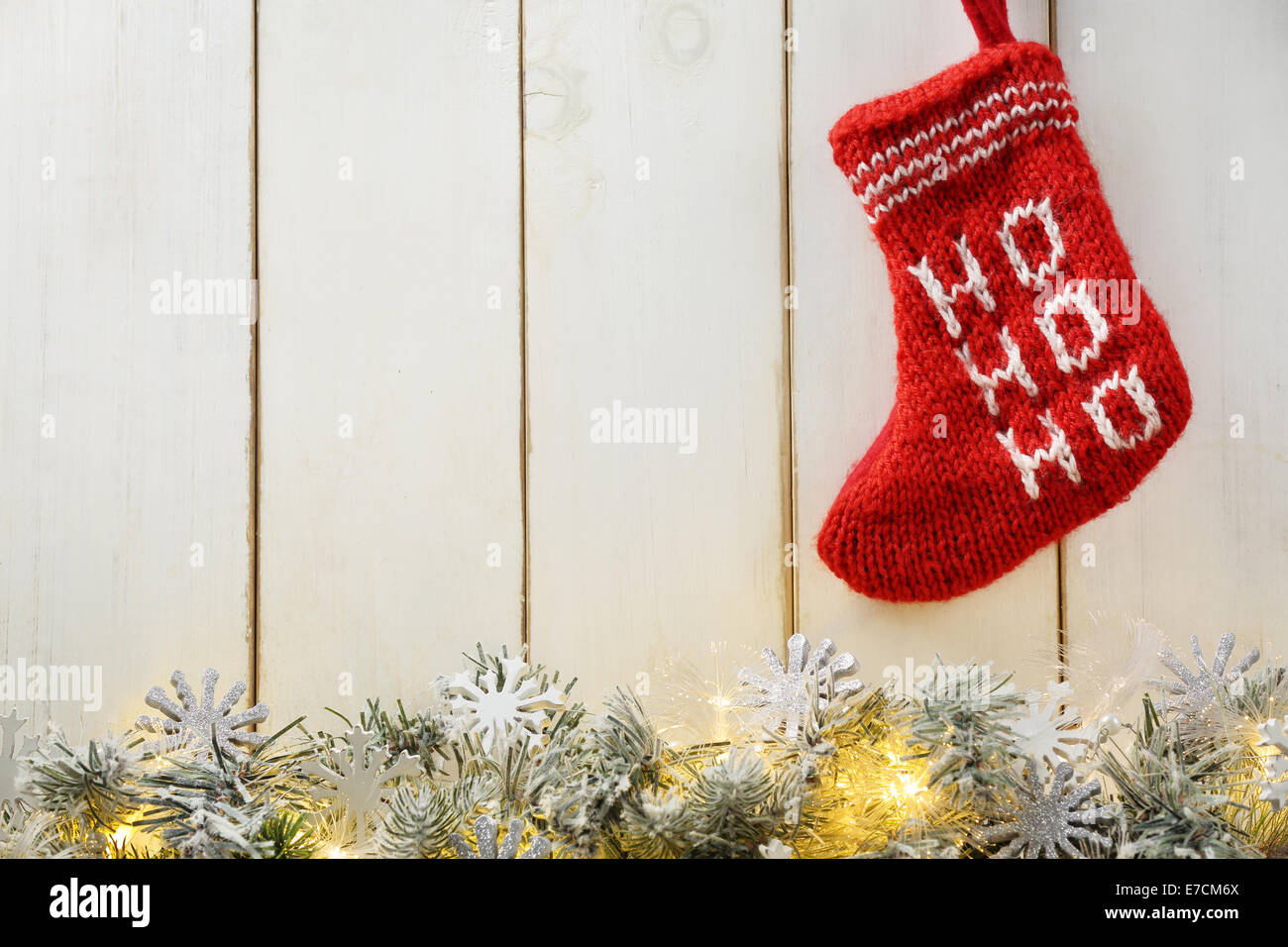 Tanne Zweig mit Weihnachtsbeleuchtung und Weihnachtsmann rot Strumpf auf Holz Hintergrund Stockfoto