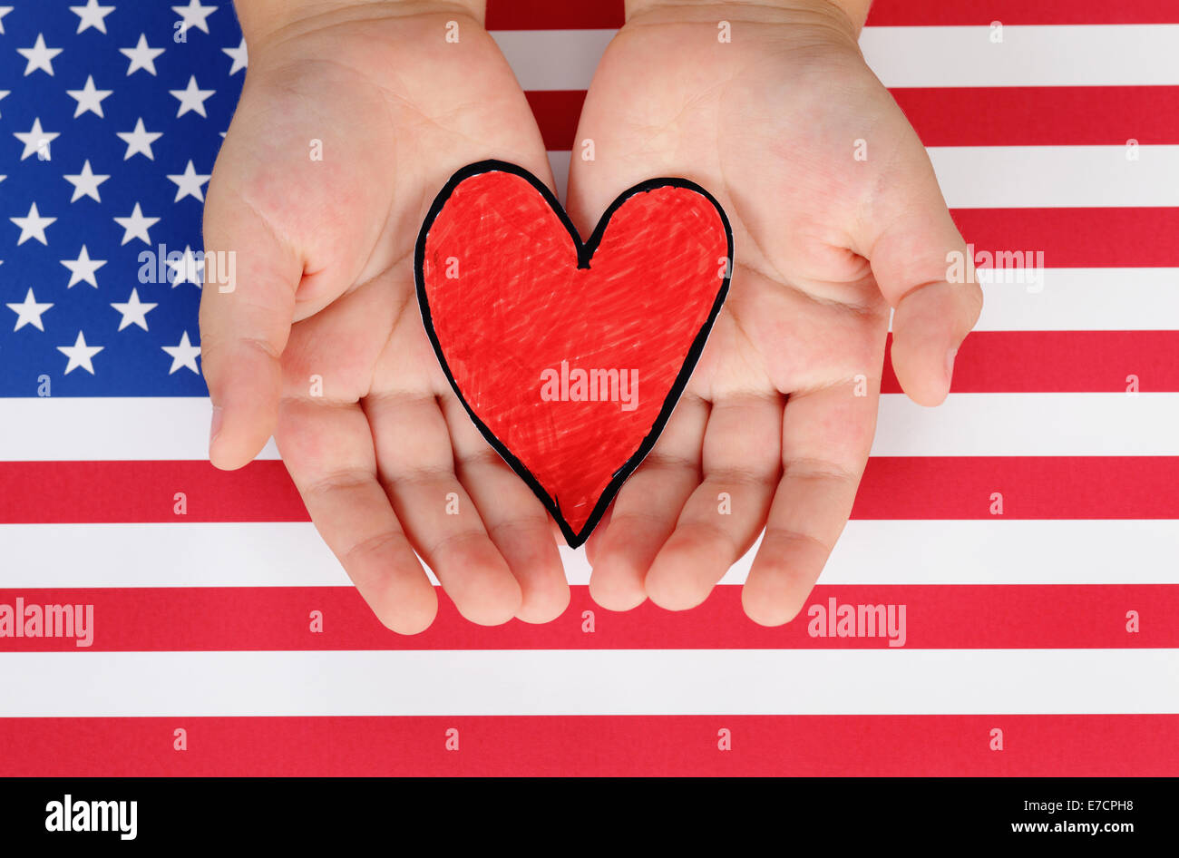 Hände des Kindes halten rote Papierherz gegen amerikanische Flagge. Stockfoto