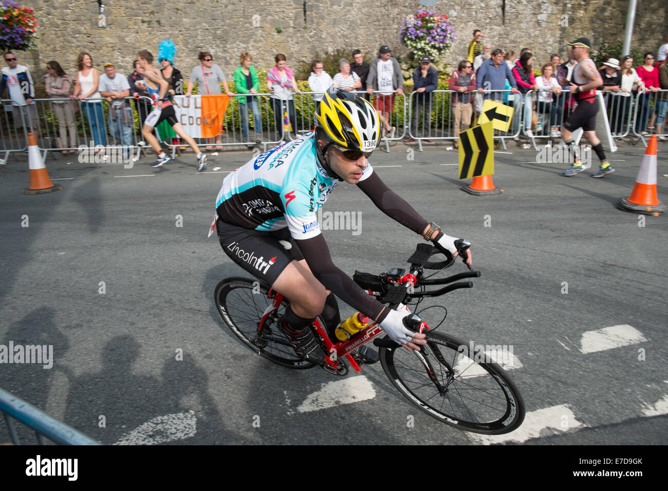 Tenby, Pembrokeshire, Wales, UK. 14. Sep, 2014. Fahrrad-Abschnitt der IRONMAN WALES in Tenby, Pembrokeshire, Wales. Britischer Leichtathlet Andy Newham beendete das Rennen in 14 Stunden, 7 Minuten 27 Sekunden. Dieser Triathlon umfasst 2,4 Meilen schwimmen, 112 Meile Fahrrad fahren und 26,2 Meilen laufen. Mit Kufen im Hintergrund auf letzten Marathon Teil. Bildnachweis: Paul Quayle/Alamy Live-Nachrichten Stockfoto