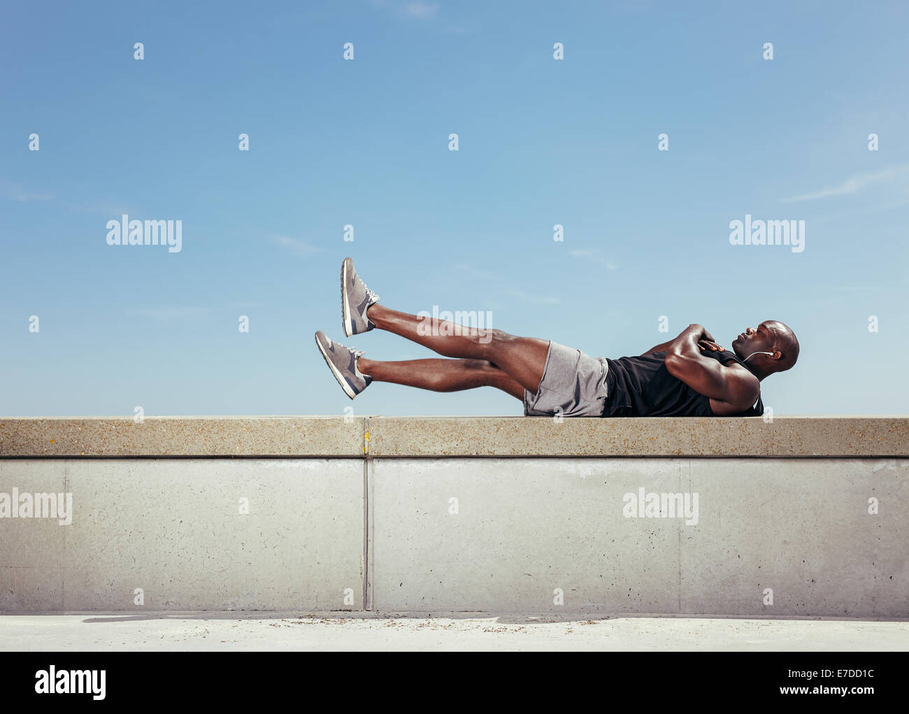 Junge Afrikaner Dehnung liegend an einer Wand durch Gehweg im Freien Training zu tun. Muskulösen jungen Fitness Modell Ausübung Stockfoto