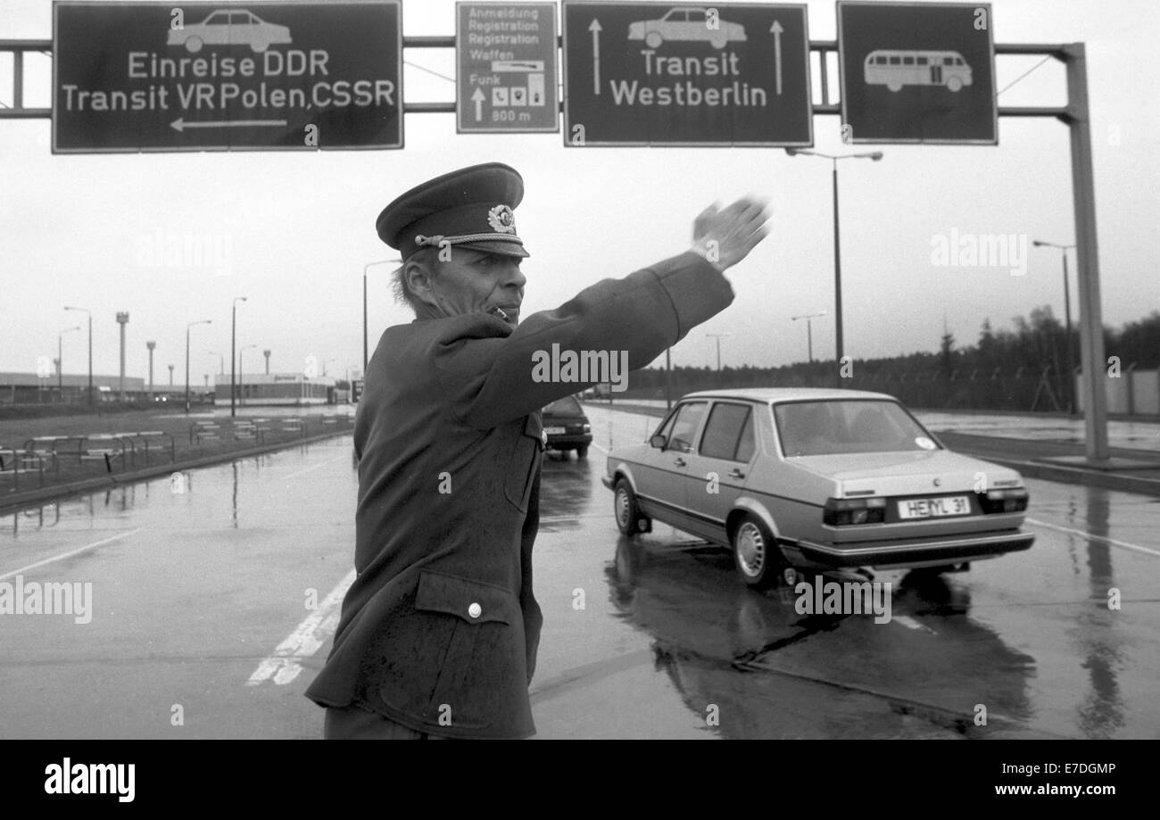 Eine ostdeutsche Grenzschutzbeamte leitet ankommende Fahrzeuge auf den Bahnen für Eingang in die DDR oder die Transitstrecke nach West-Berlin am Grenzübergang Marienborn, Deutschland, Februar 1990. Foto: Eberhard Kloeppel Stockfoto