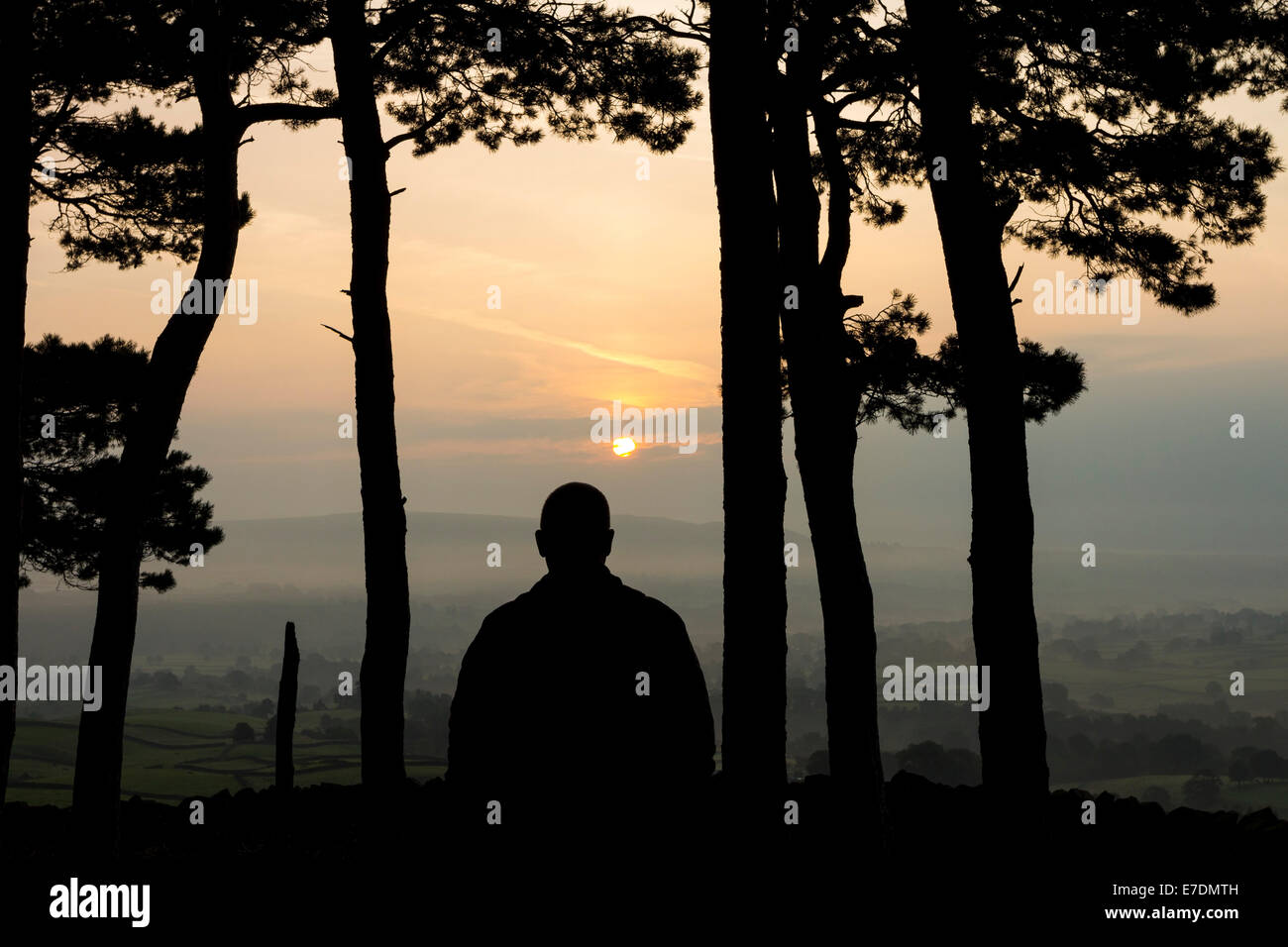 Silhouette einer Person, die den Sonnenaufgang auf Misty Morning, Kirkcarrion, Pennines, County Durham, England Stockfoto