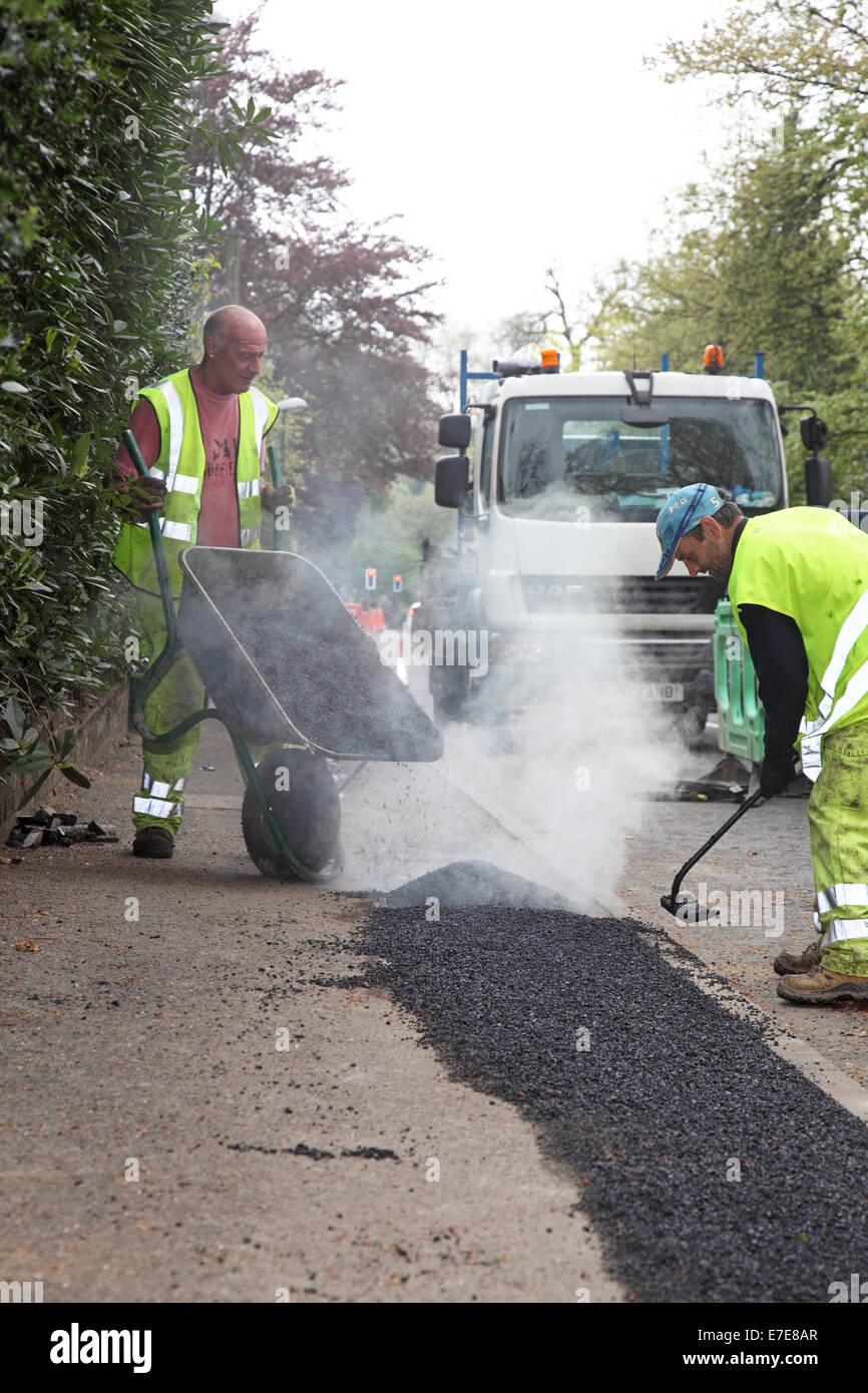 Arbeiter verlegen Asphalt zu einem Wanderweg nach der Installation des neuen Glasfaser-Kabel für high-Speed Breitband Stockfoto