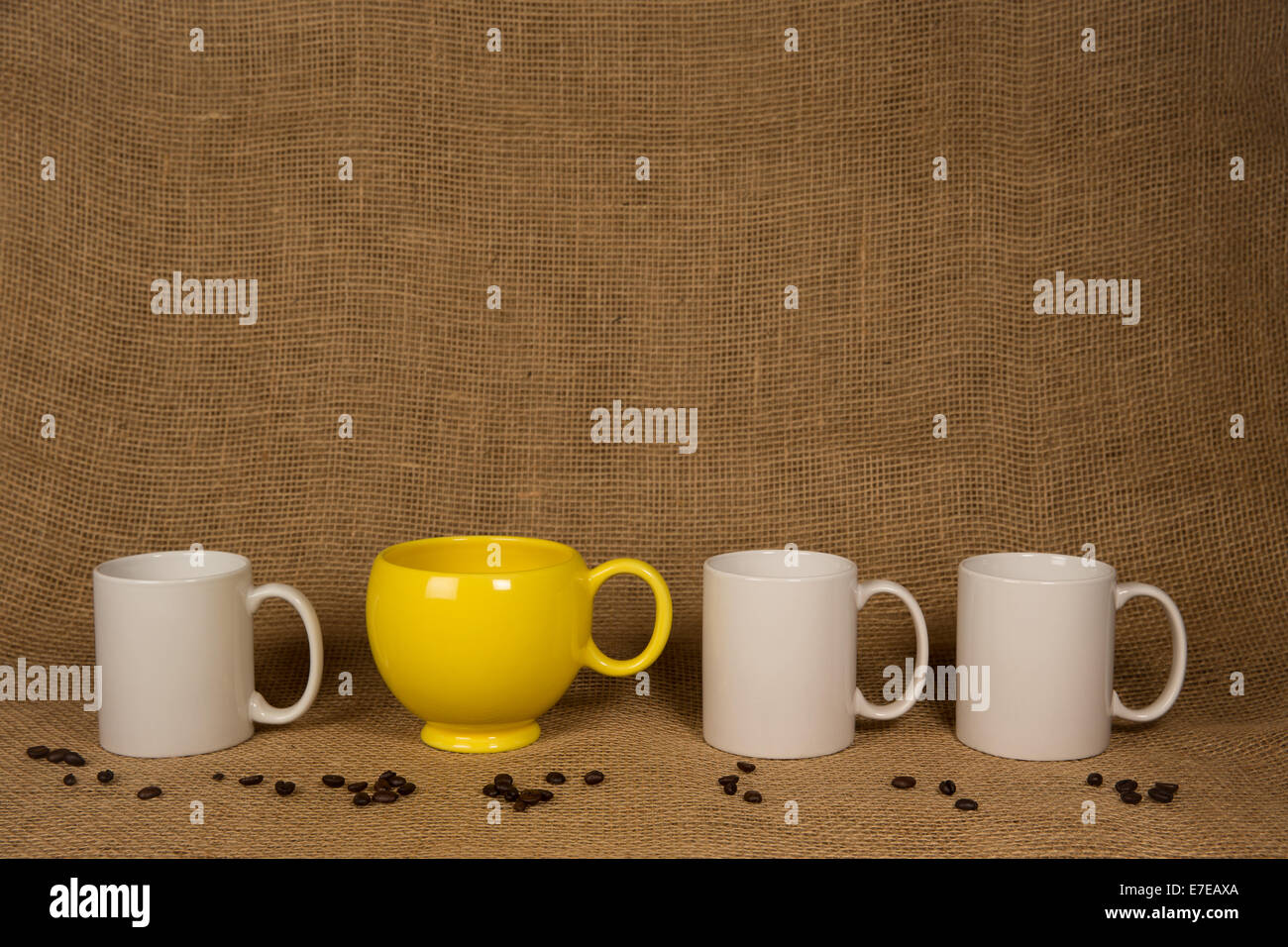 Kaffee-Haferl Hintergrund.  Eine eindeutige gelbe Becher, drei weißen, Kaffeebohnen auf Sackleinen.  Kopieren Sie Platz auf Tassen und über ihnen. Stockfoto